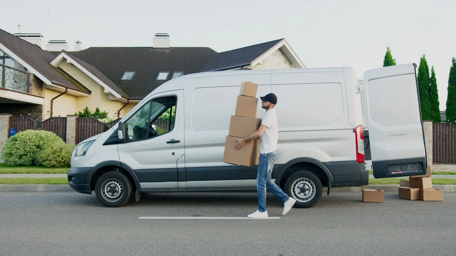 Transporter mit geöffneten Türen und Kartons vor einem Wohnhaus, Symbolbild
